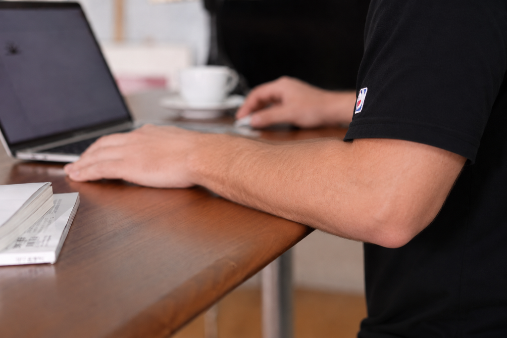 Forearm resting comfortably on the curved black walnut desktop edge