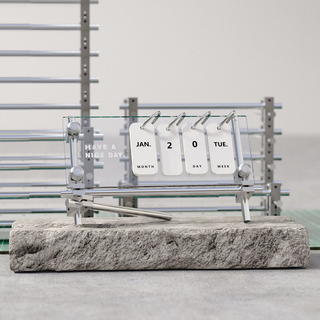 Acrylic flip desk calendar with a silver metal frame on a stone display block
