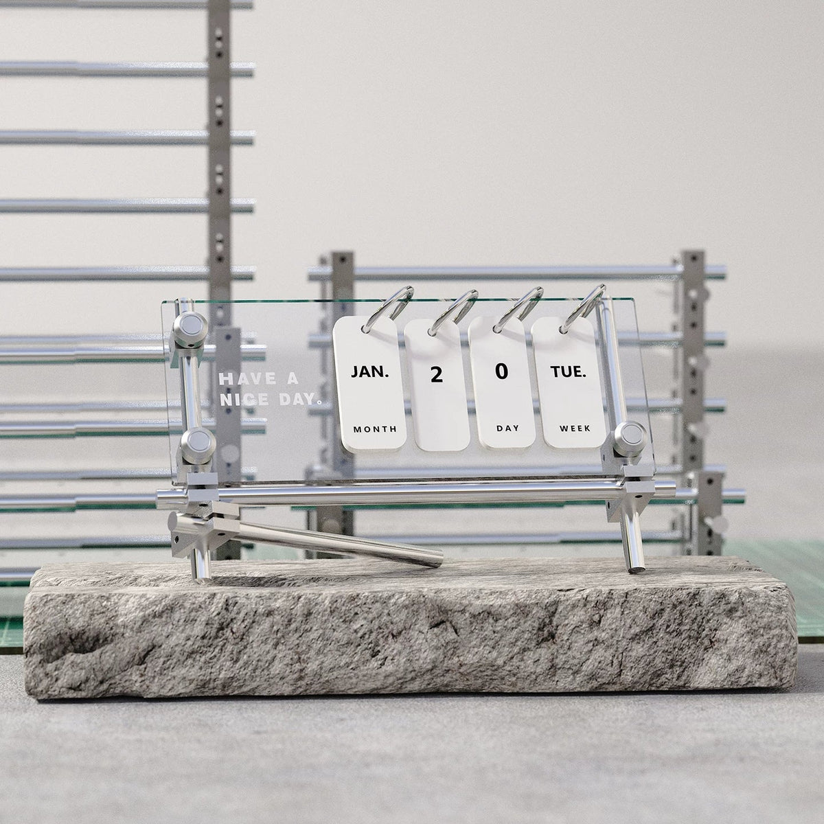 Acrylic flip desk calendar with a silver metal frame on a stone display block