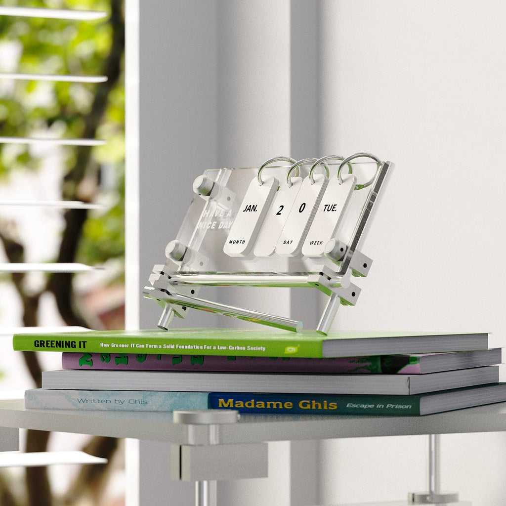 Acrylic flip calendar styled on stacked books beside a window