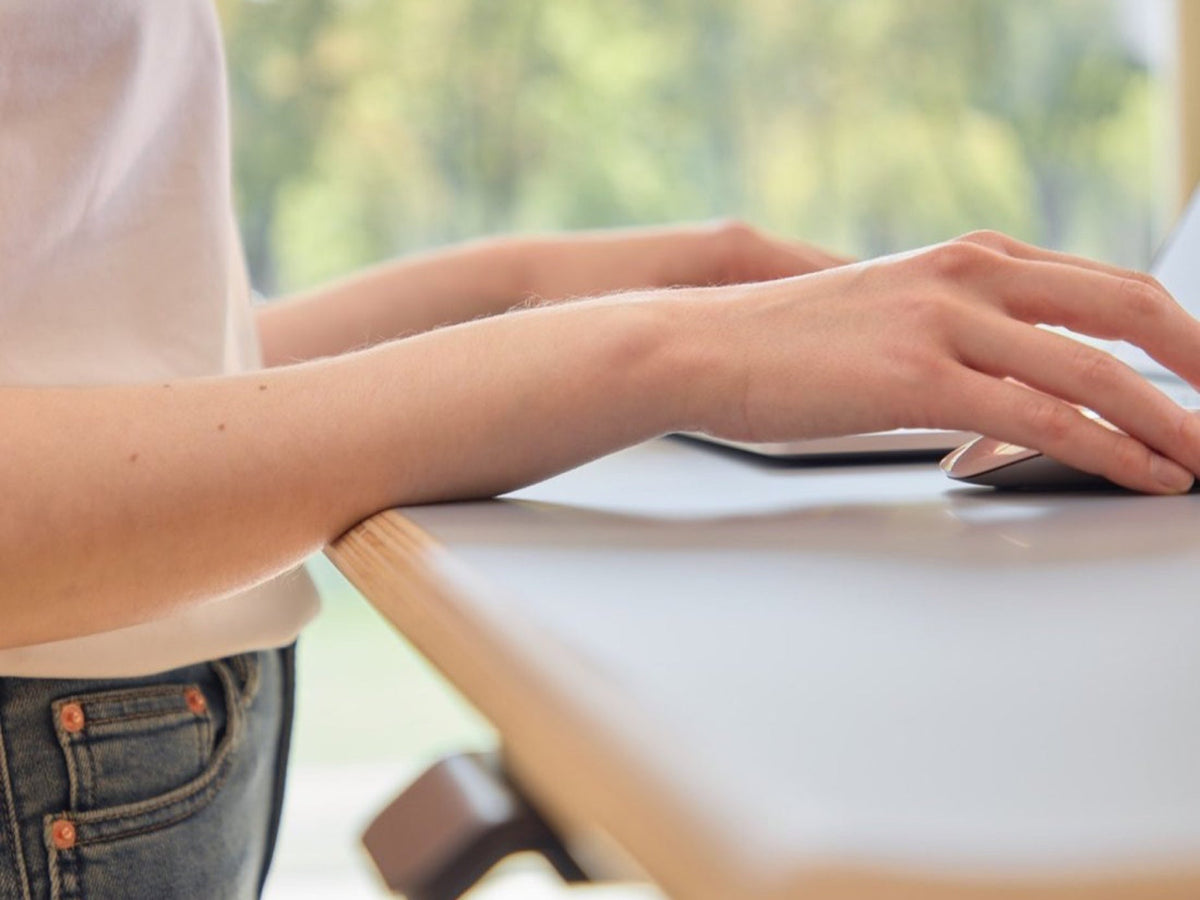 Forearms resting on the curved ComfortEdge of the Clear Sky Blue Ease Standing Desk