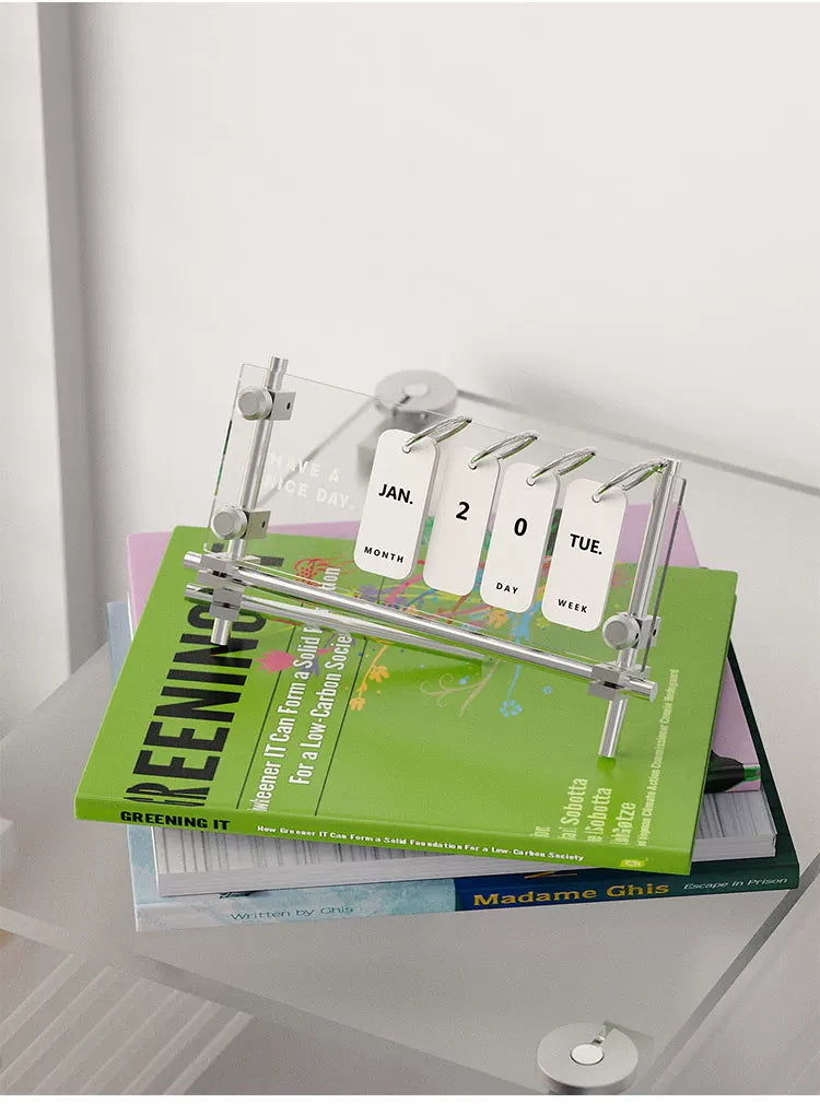 Acrylic flip calendar placed on books in a quiet desk setting