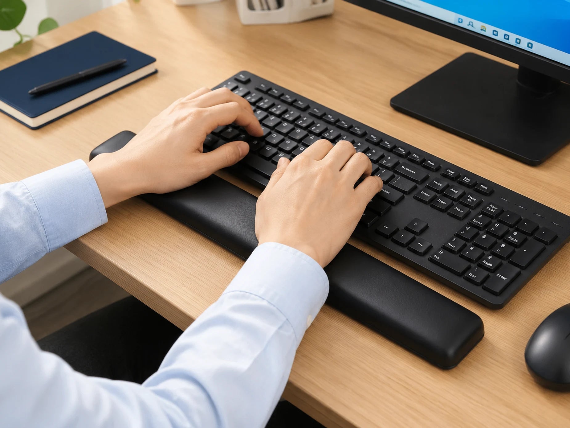 Hands typing with both wrists supported by the black keyboard wrist rest