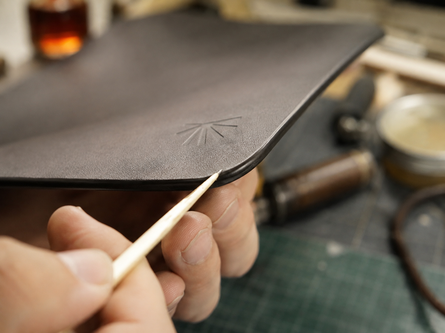 Craftsperson applying finish to the Napa desk mat edge